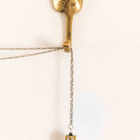 Genuine Hohner harmonica necklace with a brass chain hanging from a brass hook