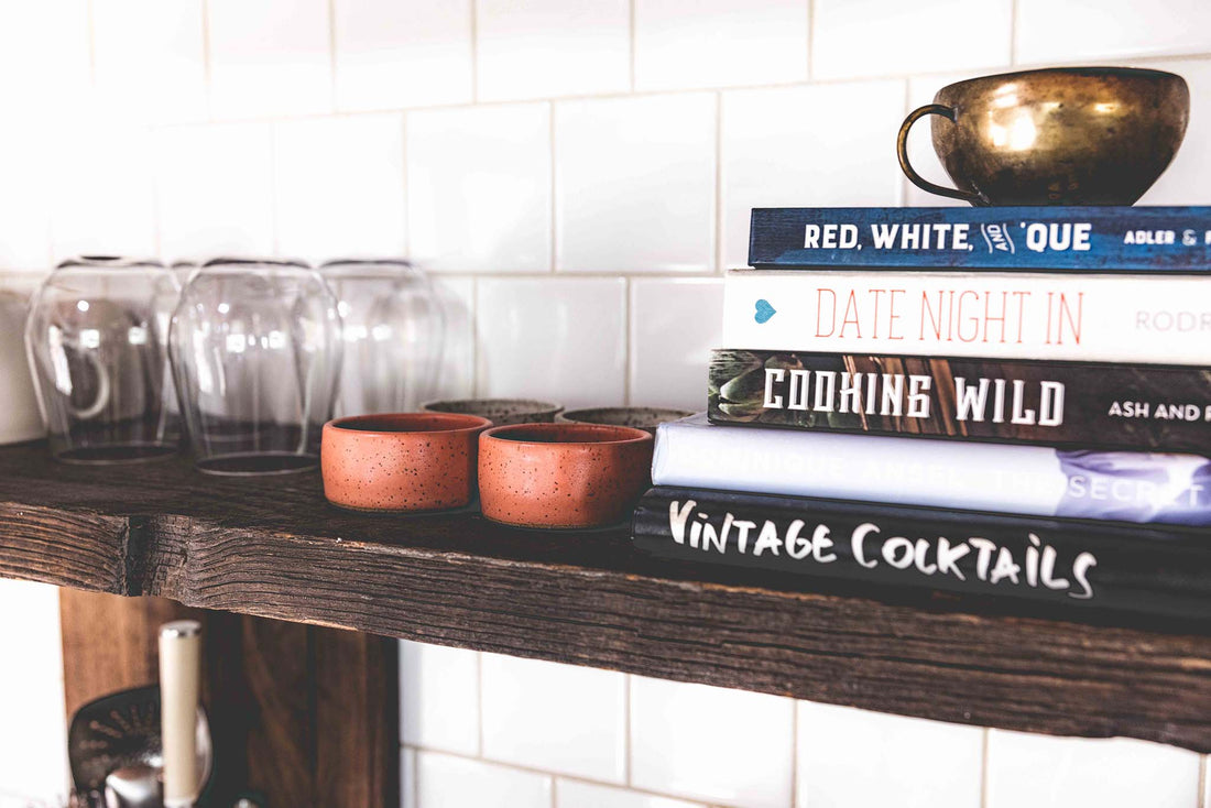 Two pink speckled clay mezcal copitas on a kitchen shelf