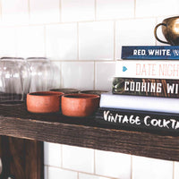 Two pink speckled clay mezcal copitas on a kitchen shelf