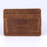Close up view of slim minimalist wallet made from brown genuine leather with two card pockets shown and embossed with text "Sound As Ever"