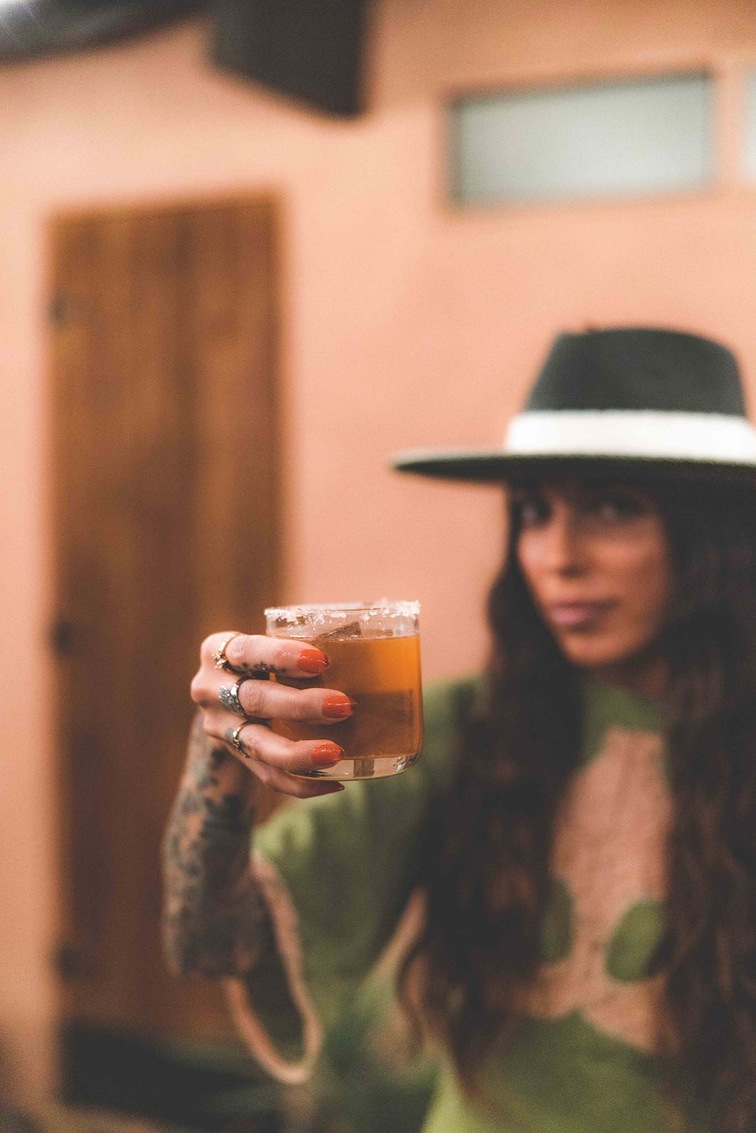 Whiskey stone in a glass with a mixed drink held up by a woman