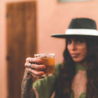Whiskey stone in a glass with a mixed drink held up by a woman