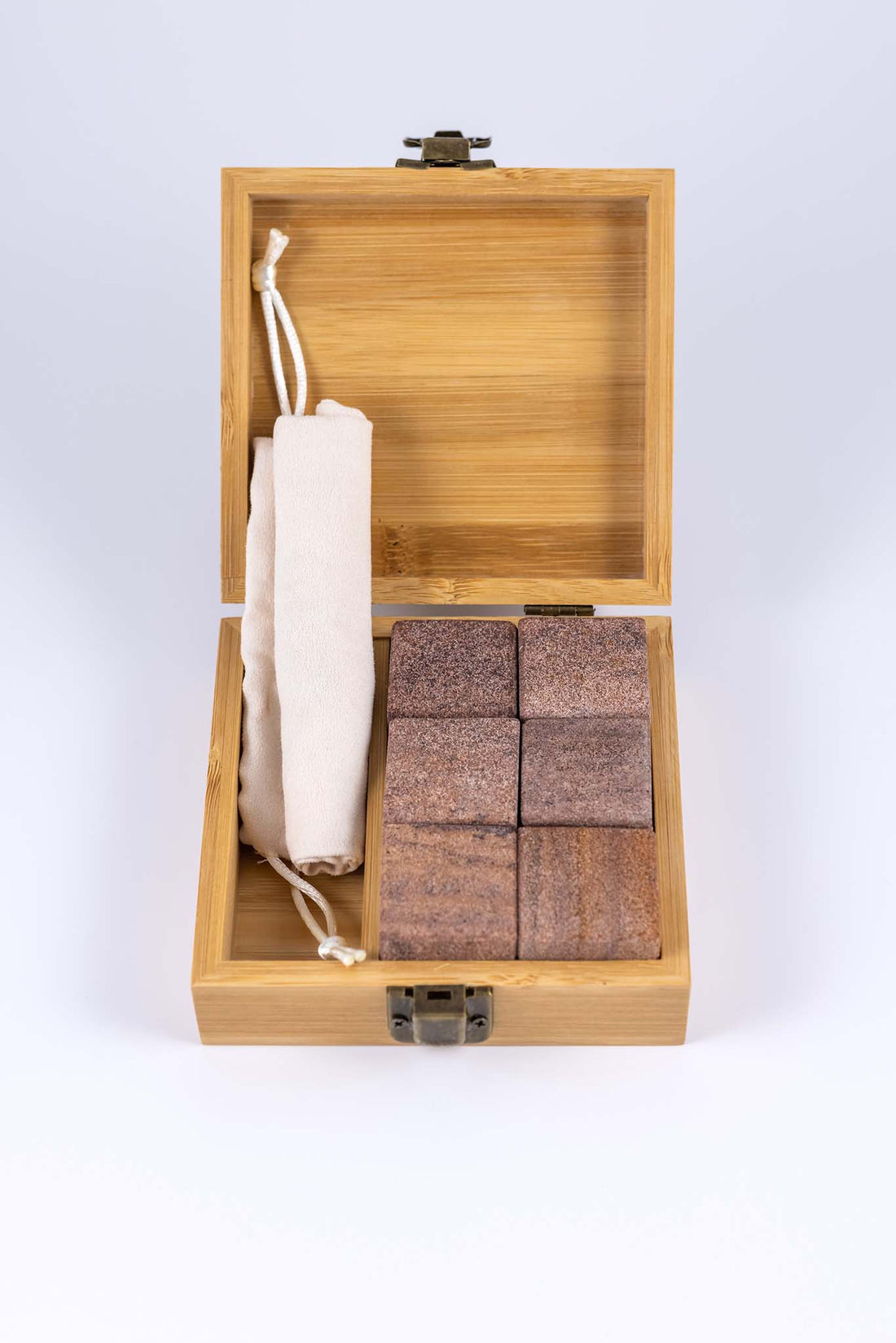 Whiskey stone set with the tan wooden box open to reveal six quartz whiskey stones and a divider with a cotton draw string bag