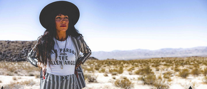 Woman in desert wearing black felt hat and a white shirt with text "Gram Parson and the Fallen Angels"