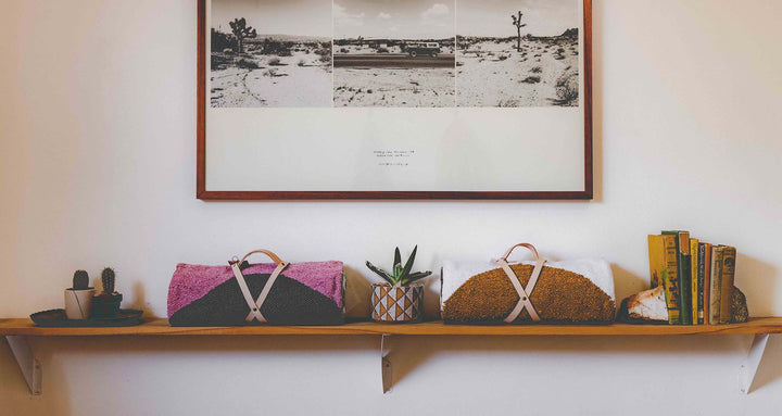 Two rolled up boho throw blankets on a shelf with a hanging picture in black and white of joshua trees and an old classic car