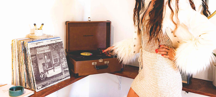 Record player on a shelf with a stylish woman in a furry white coat sets the record on
