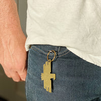 Brass keychain with thunderbird design hanging from a man's jean pocket