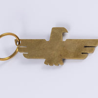 Brass keychain with minimalist thunderbird design that doubles as a bottle opener laid flat horizontally