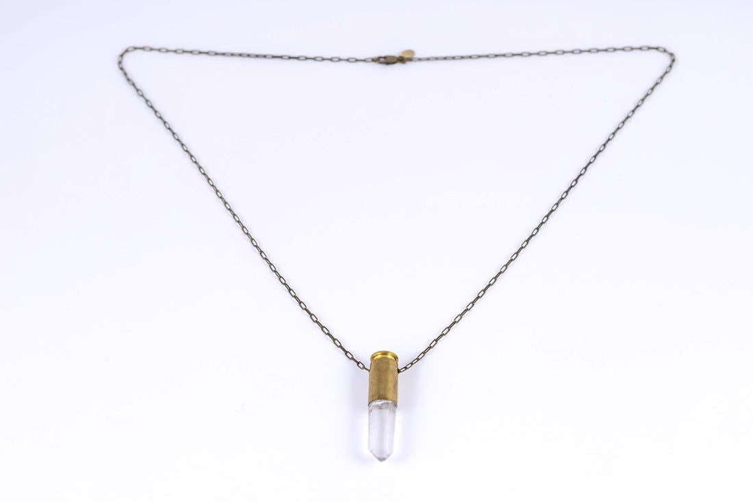 Side angle view of bullet quartz necklace with brass bullet casing over clear quartz with an antique brass chain and clasp