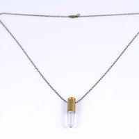 Side angle view of bullet quartz necklace with brass bullet casing over clear quartz with an antique brass chain and clasp