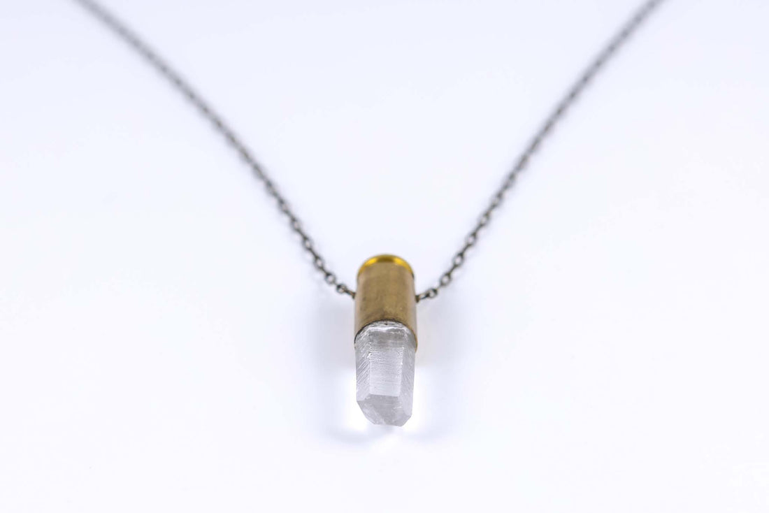 Close up of clear quart in bullet quartz necklace with brass bullet casing and antique brass chain