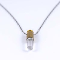 Close up of clear quart in bullet quartz necklace with brass bullet casing and antique brass chain