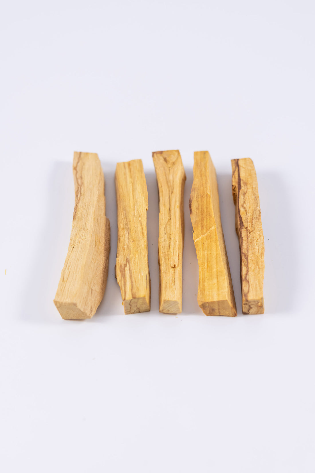 Ethically sourced palo santo sticks laid down in a row of similar but varying thicknesses