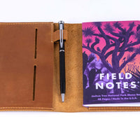 Close up view of inside of the leather field notes wallet with a pen and field notes memo book inside the pocket