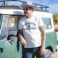 Man leaning on side of car wearing Gram Parsons Fallen Angels t-shirt and wool hat