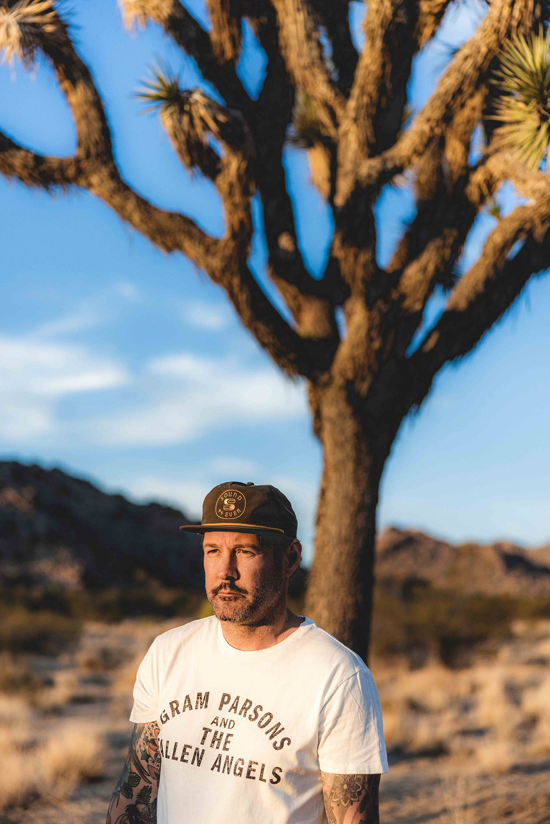 Man wearing Gram Parsons and the Fallen Angels white distressed t-shirt with Joshua tree in background