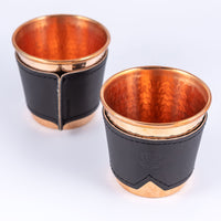 Two hammered copper cups with black leather sleeves stamped with Sound As Ever Logo on the front and the sewn seam in the back