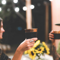 Two women having drinks at night drinking from the hammered copper cups with black leather sleeves