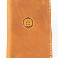 Handmade leather passport wallet made from genuine leather featuring embossed 'Here For Now' Ouroboros design