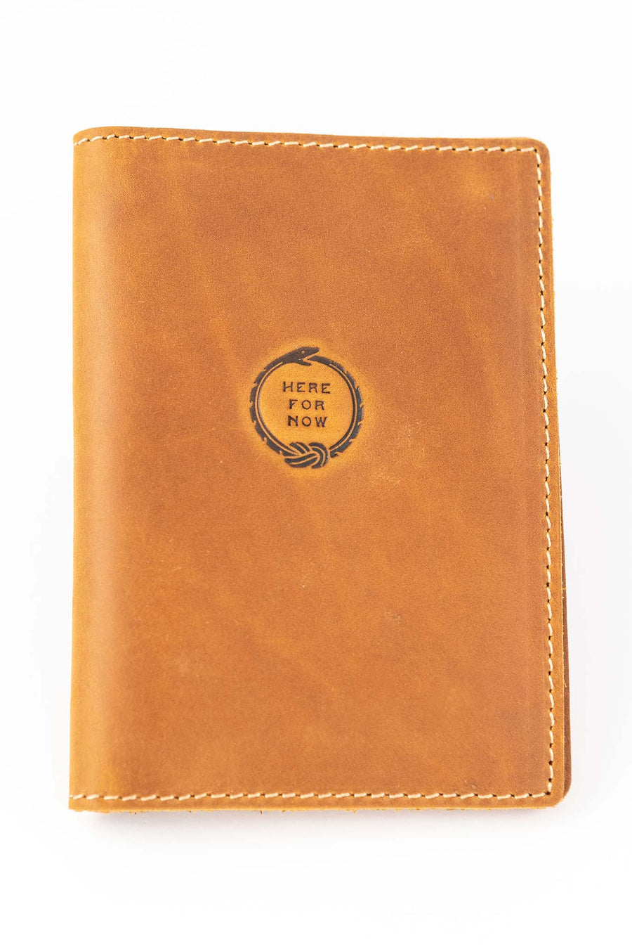 Handmade leather passport wallet made from genuine leather featuring embossed 'Here For Now' Ouroboros design