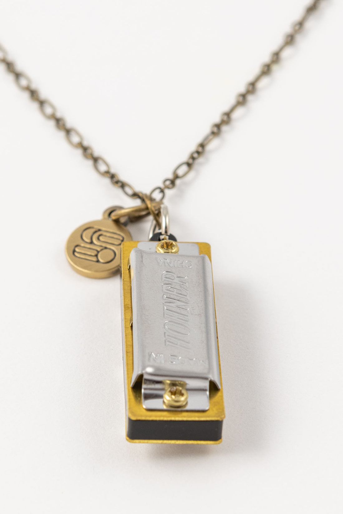 Genuine Hohner harmonica necklace with brass charm with Sound as Ever logo