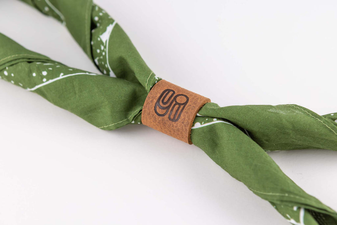 Close up view of the leather bandana slide or ring acting as a bolo tie for a green bandana