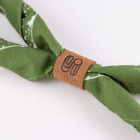 Close up view of the leather bandana slide or ring acting as a bolo tie for a green bandana