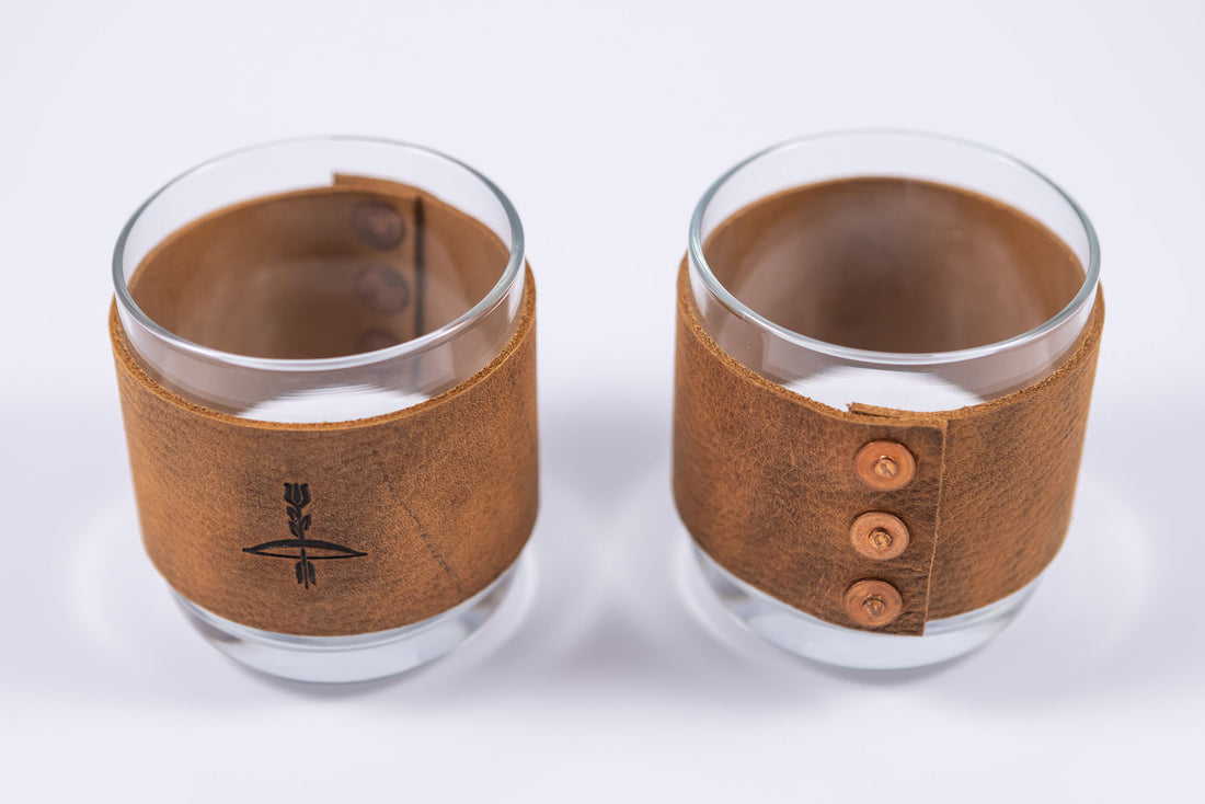 Handmade leather wrapped whiskey glasses with arrow design and brass buttons close up view