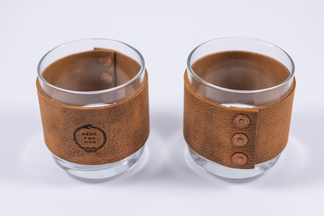 Handmade leather wrapped whiskey glasses with Ouroboros "Here For Now" design and brass buttons close up view