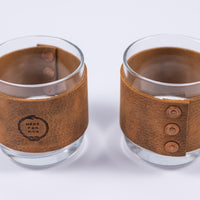 Handmade leather wrapped whiskey glasses with Ouroboros "Here For Now" design and brass buttons close up view