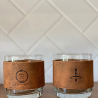 Leather wrapped whiskey glasses with embossing or stamped leather design of Ouroboros "Here For Now" and another with arrow design