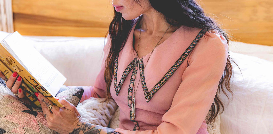 Pocket knife necklace worn by woman in pink long sleeve shirt reading a book