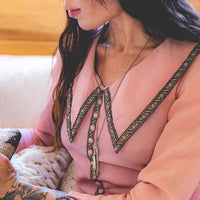 Pocket knife necklace worn by woman in pink long sleeve shirt reading a book