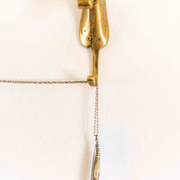 Pocket knife necklace made from brass and faux bull horn that hands with its brass chain from from a brass hook shaped like a horse head