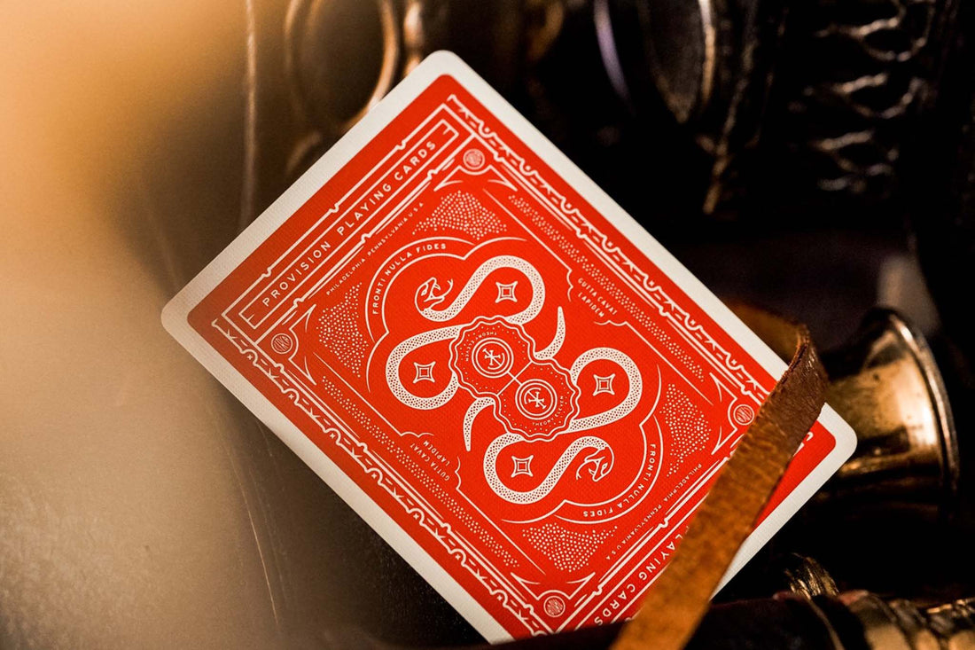 Red top of a premium playing card from Provision Brand showing swirling white serpent designs on a bright red background