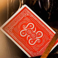 Red top of a premium playing card from Provision Brand showing swirling white serpent designs on a bright red background