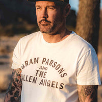 Man wearing Sound As Ever snapback hat with yellow logo and olive green material and white Gram Parsons and the Fallen Angels official classic t-shirt