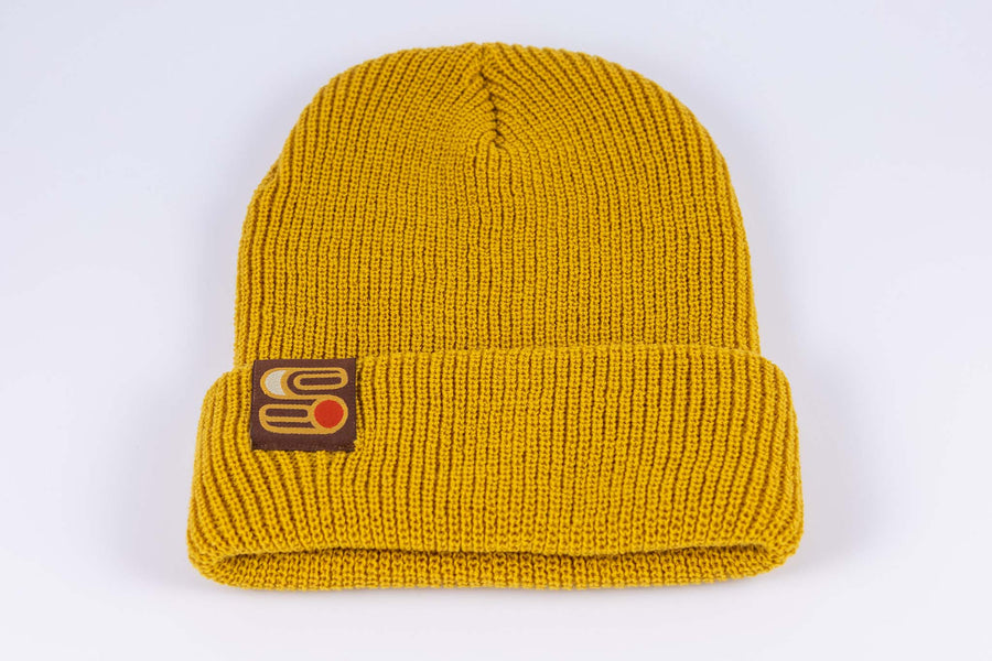 Close up view of yellow Sound As Ever beanie with the Sound as Ever logo on a tag