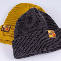 Close up view of Sound As Ever Beanie shown in yellow and gray colors with Sound as Ever Logo tag