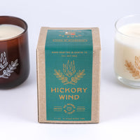 Soy wax candle in "Hickory Wind" scent showing design of two plant branches and fire above