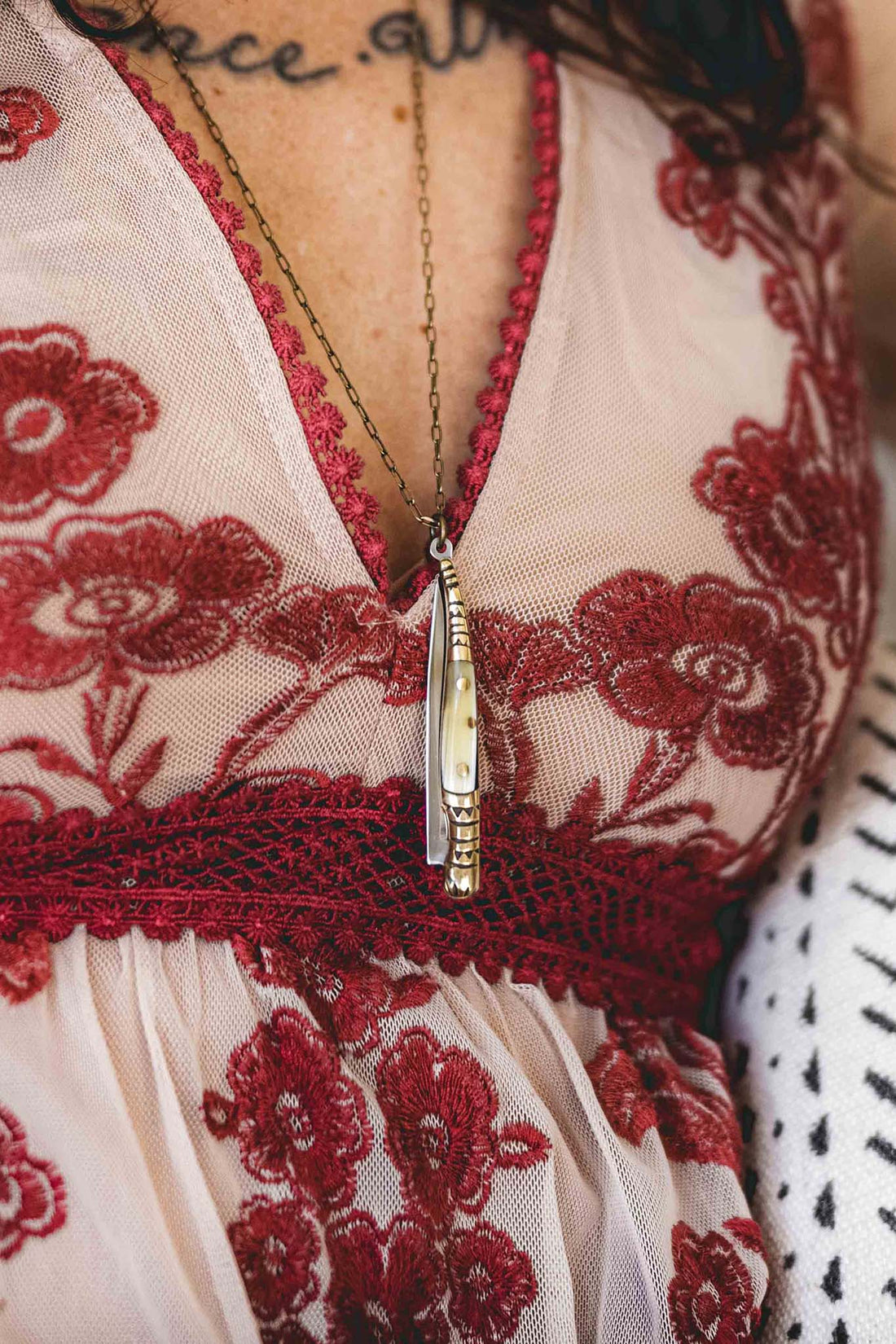 Pocket knife necklace with bullhorn style handle and stamped decorative brass worn with a brass chain around woman's neck