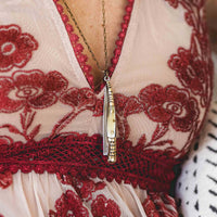 Pocket knife necklace with bullhorn style handle and stamped decorative brass worn with a brass chain around woman's neck