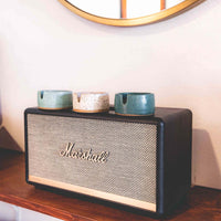 Three stoneware ashtrays each a different color of speckled clay- white, light blue, and darker greenish blue on top of a Marshall speaker