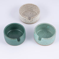 Three stoneware ashtrays each a different color of speckled clay- white, light blue, and darker greenish blue