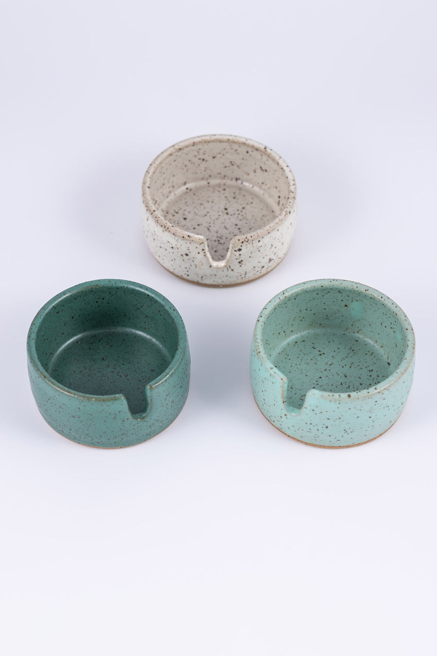 Three stoneware ashtrays each a different color of speckled clay- white, light blue, and darker greenish blue