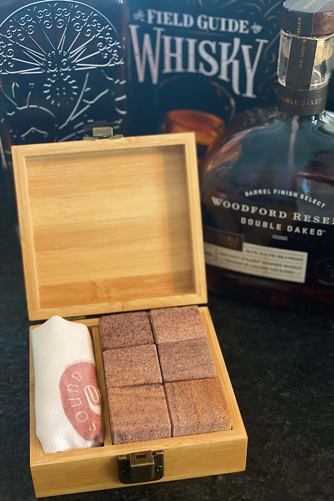 Whiskey stone set with six cubic stones made from light pink or tan desert striped quartz inside a wood box and with a bag featuring the Sound As Ever logo
