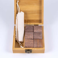 Whiskey stone set with the tan wooden box open to reveal six quartz whiskey stones and a divider with a cotton draw string bag